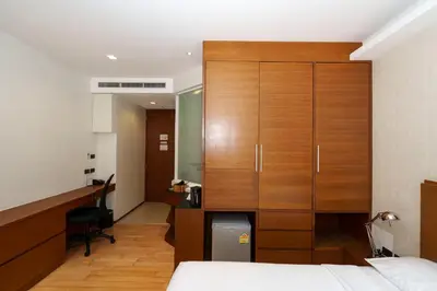 a bedroom with a wooden cabinet and a desk at Marvin Suites Hotel in Bangkok