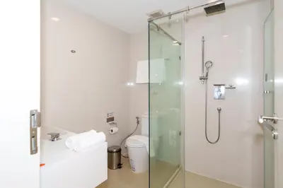 a bathroom with a glass shower with a toilet at Marvin Suites Hotel in Bangkok