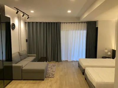 a bedroom with a bed and a couch and a window at Bangyai Inn-private room in Nonthaburi