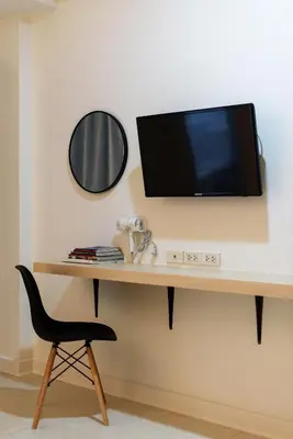 a desk with a television on a wall with a chair at Grand Watergate Hotel in Bangkok
