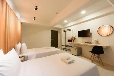 a hotel room with two beds and a desk at Grand Watergate Hotel in Bangkok