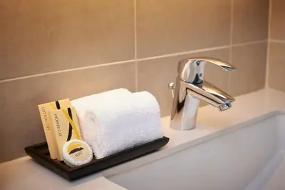 a bathroom sink with a towel and a faucet at Amp Am House Bangkok Hotel in Bangkok