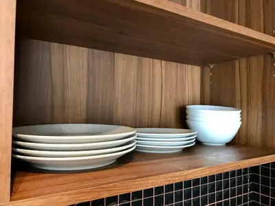 three plates and bowls on a shelf in a cabinet at Amp Am House Bangkok Hotel in Bangkok