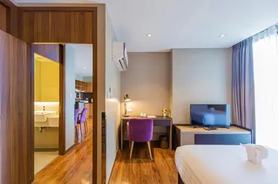 a hotel room with a bed and a desk and a tv at Amp Am House Bangkok Hotel in Bangkok