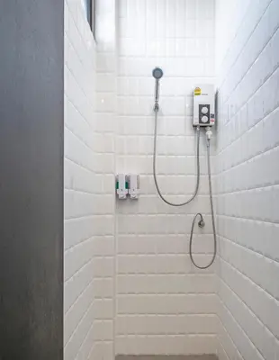 a shower in a bathroom with white tiles at Lost Inn BKK in Bangkok