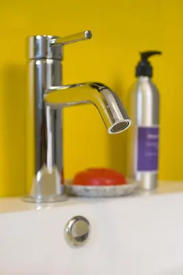 a sink with a faucet and a bottle of soap at T Series Place Serviced Apartment in Bangkok