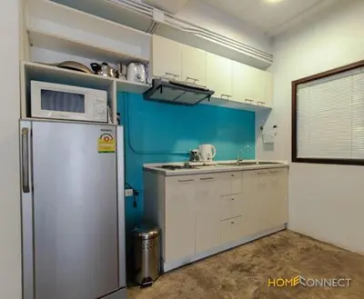 a kitchen with a white refrigerator and a blue wall at T Series Place Serviced Apartment in Bangkok