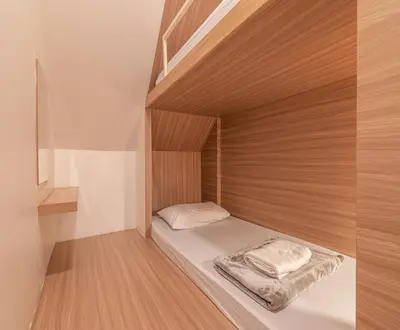 a small bed in a small room with wooden walls at The Victory View in Bangkok