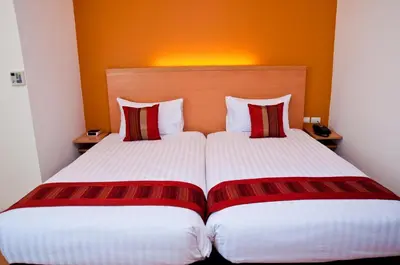 a hotel room with two beds with red and white pillows at Iyarin @ Tuk Chang Hotel in Bangkok
