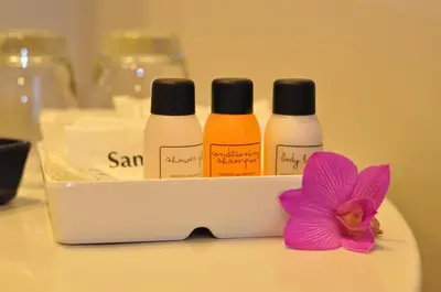 three bottles of soap and a pink flower on a counter at Iyarin @ Tuk Chang Hotel in Bangkok