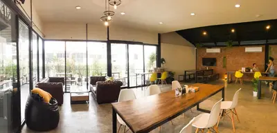 a dining room with a table and chairs and windows at the CAPSULE by UnionSPACE in Bangkok