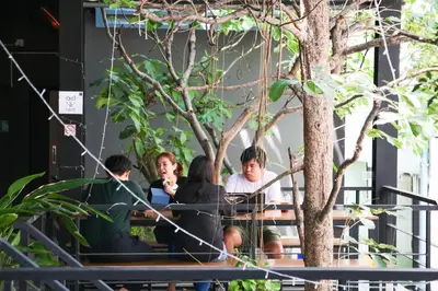 a group of people sitting at a table under a tree at the CAPSULE by UnionSPACE in Bangkok