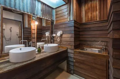two sinks in a bathroom with wooden walls at Suneta Hostel Khaosan in Bangkok