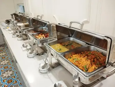 a row of trays of food in a kitchen at Siri Heritage Bangkok Hotel in Bangkok