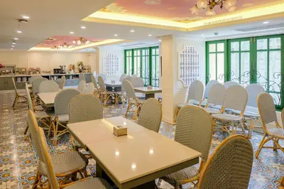 a dining room with tables and chairs and windows at Siri Heritage Bangkok Hotel in Bangkok