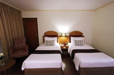 a hotel room with three beds and a chair at Grand Tower Inn Rama 6 in Bangkok