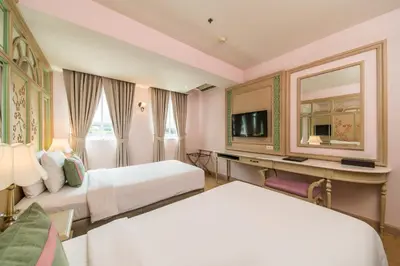a hotel room with two beds and a television at La Petite Salil Sukhumvit 11 in Bangkok
