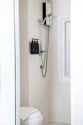 a bathroom with a white toilet and a shower at Nantra Sukhumvit 39 in Bangkok