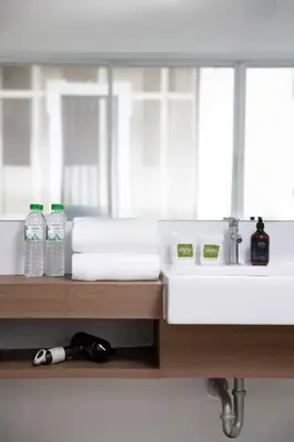 a bathroom with a sink and two bottles of water at Nantra Sukhumvit 39 in Bangkok