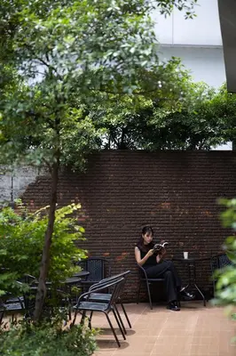 a woman sitting on a bench against a brick wall at Nantra Sukhumvit 39 in Bangkok