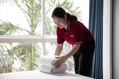 a woman putting towels on top of a bed at Nantra Sukhumvit 39 in Bangkok
