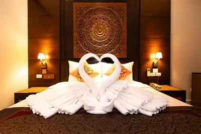 two white swans are sitting on a bed at Baan Sukhumvit Soi 18 in Bangkok