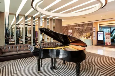 a black piano in a lobby with a couch at TK Palace Hotel & Convention Bangkok in Bangkok