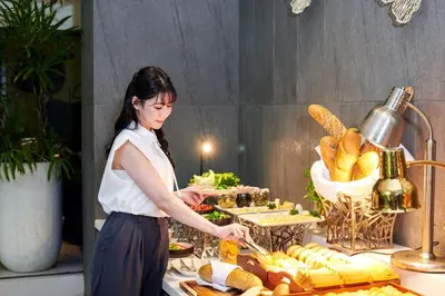 a woman standing in front of a buffet of food at TK Palace Hotel & Convention Bangkok in Bangkok