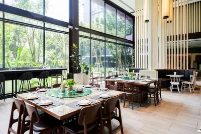 a restaurant with wooden tables and chairs and large windows at TK Palace Hotel & Convention Bangkok in Bangkok