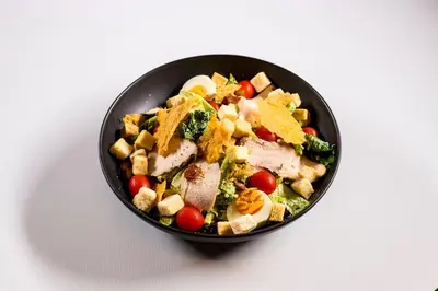 a black bowl filled with a salad on a table at TK Palace Hotel & Convention Bangkok in Bangkok