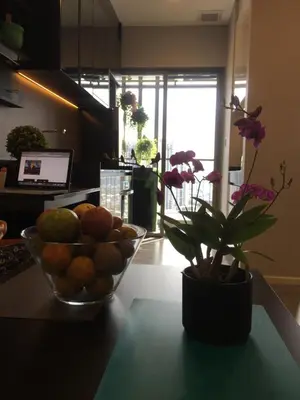 a bowl of fruit on a counter with a vase of flowers at Bangkok view,Luxurious 1 Bedroom Sathon in Bangkok