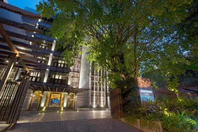 a building with a tree in front of it at Riva Surya Bangkok in Bangkok