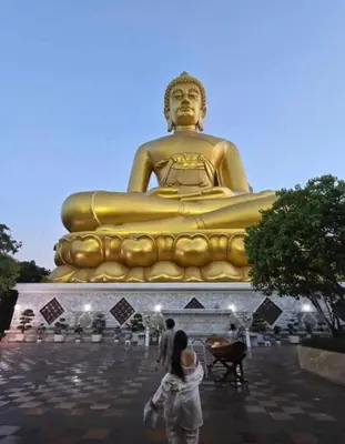 a woman standing in front of a giant golden statue at 51 Suanplu Residence in Bangkok