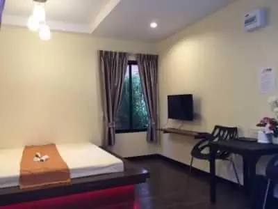 a bedroom with a bed and a desk and a window at Angie Resort at Sapan Mai in Bangkok