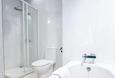 a white bathroom with a toilet and a shower at Grand Howard Hotel Bangkok in Bangkok