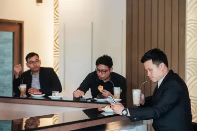 a group of men sitting at a table eating food at Grand Howard Hotel Bangkok in Bangkok