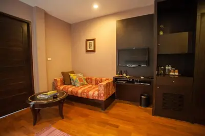 a living room with a couch and a television at Sala Arun in Bangkok