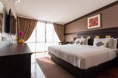 a bedroom with a large bed and a large window at Sala Arun in Bangkok