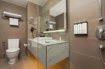 a bathroom with a toilet and a sink and a mirror at Hyatt Place Bangkok Sukhumvit 1 in Bangkok