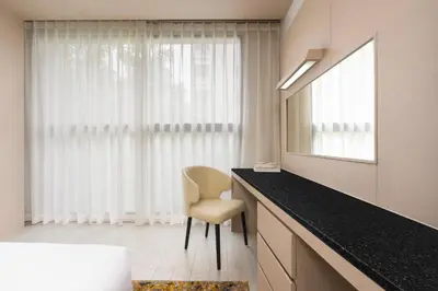 a bathroom with a vanity with a chair and a mirror at Hyatt Place Bangkok Sukhumvit 1 in Bangkok