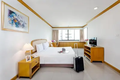 a hotel room with a bed and a suitcase at Riverine Place Hotel and Residence in Nonthaburi