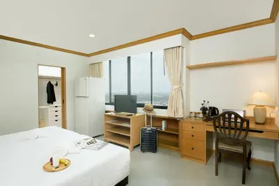 a room with a bed and a desk with a computer at Riverine Place Hotel and Residence in Nonthaburi