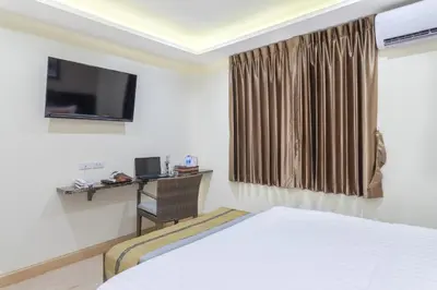 a room with a bed and a desk and a television at 4M Pratunam Hotel in Bangkok