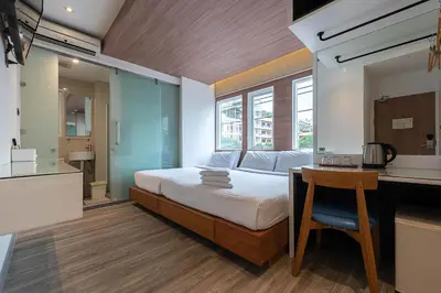 a bedroom with a bed and a desk and a kitchen at The Period Pratunam in Bangkok