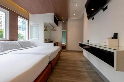 a bedroom with a large bed and a kitchen at The Period Pratunam in Bangkok