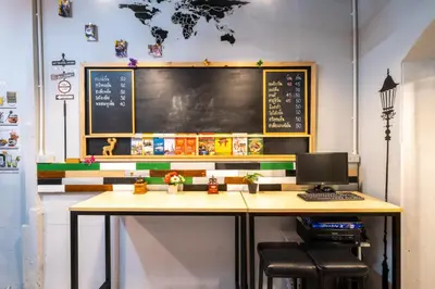 a classroom with a desk with a computer and a chalkboard at Sip N' Camp in Bangkok
