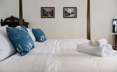 a white bed with two rolled towels on it at Baan Vajra in Bangkok