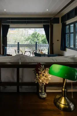 a green lamp sitting on a table next to a bed at Baan Vajra in Bangkok