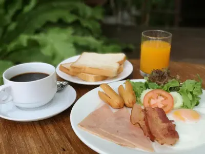 a table with two plates of food and a cup of coffee at Bansabai Hostelling International in Bangkok