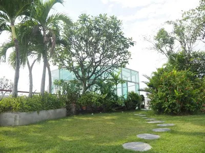 a garden with palm trees and a glass building at Bansabai Hostelling International in Bangkok